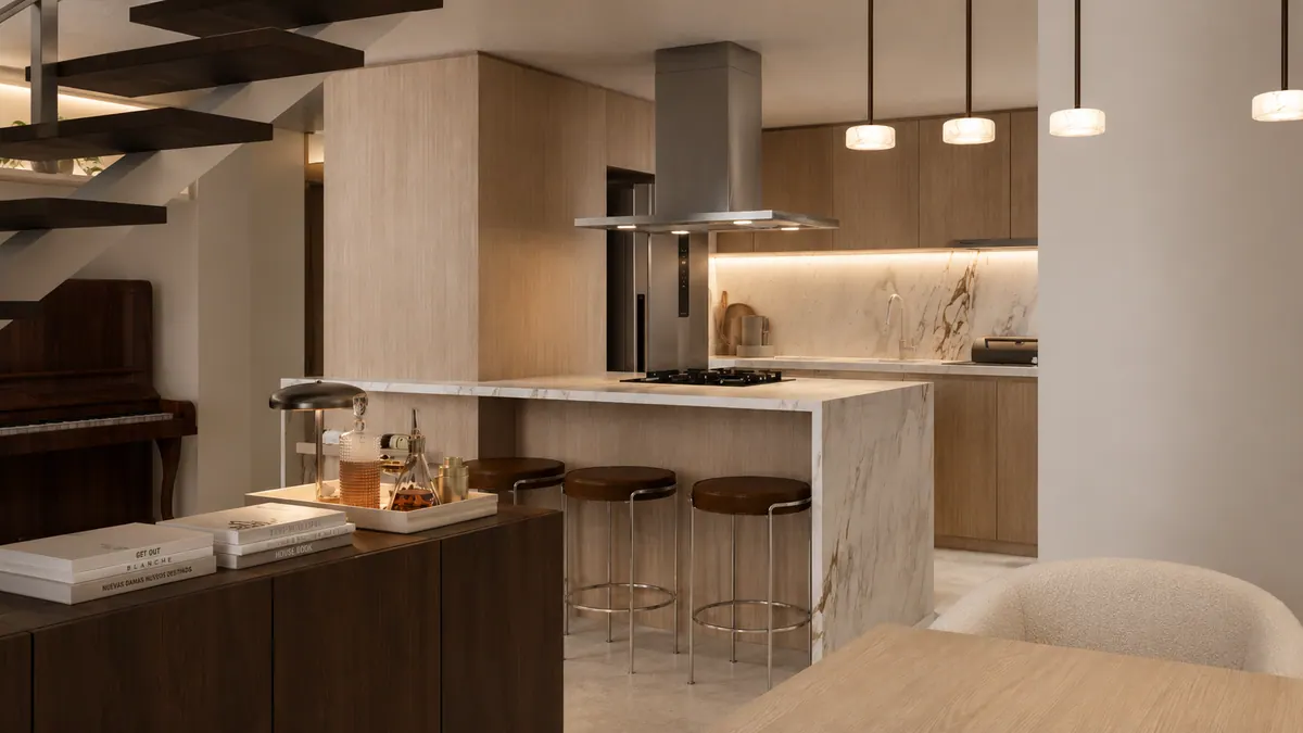 Cozinha com ilha de mármore, banquetas, coifa inox e pendentes, vista da sala