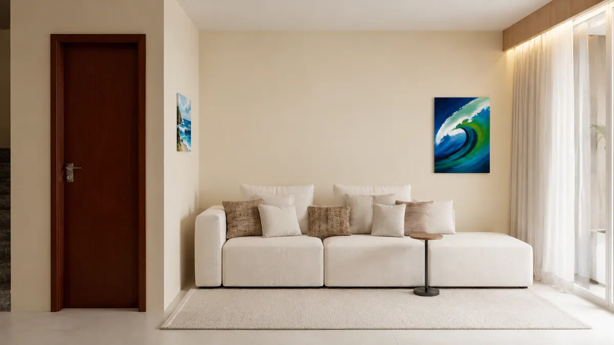 Sala de estar com sofá modular claro, almofadas, mesa lateral e quadro de onda na parede